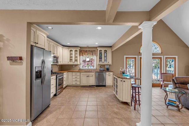 kitchen with a sink, stainless steel appliances, decorative columns, a healthy amount of sunlight, and cream cabinetry