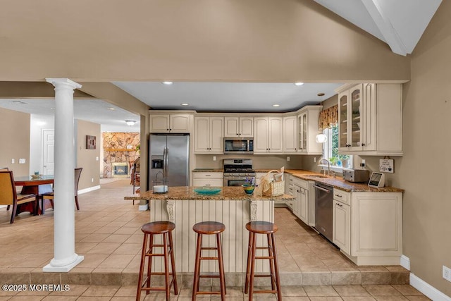 kitchen with a sink, appliances with stainless steel finishes, light tile patterned floors, and a breakfast bar