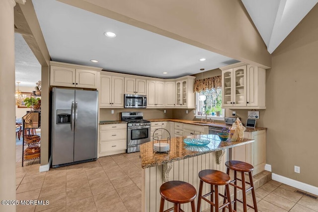 kitchen with cream cabinets, appliances with stainless steel finishes, baseboards, visible vents, and glass insert cabinets