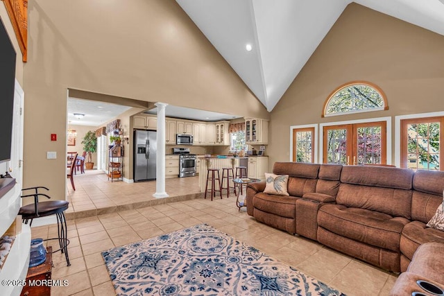 living room with ornate columns, high vaulted ceiling, and light tile patterned floors