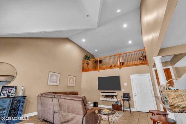 living area with baseboards, decorative columns, light tile patterned flooring, and high vaulted ceiling