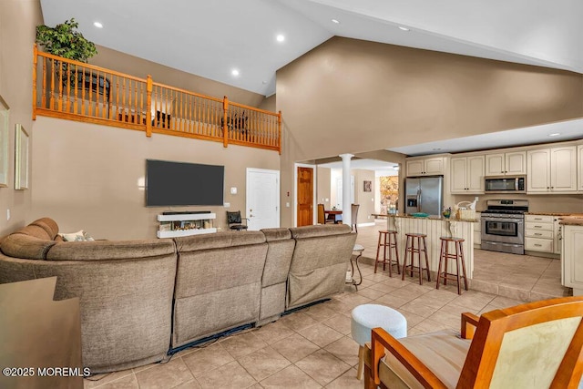 living area with light tile patterned flooring, high vaulted ceiling, decorative columns, and recessed lighting