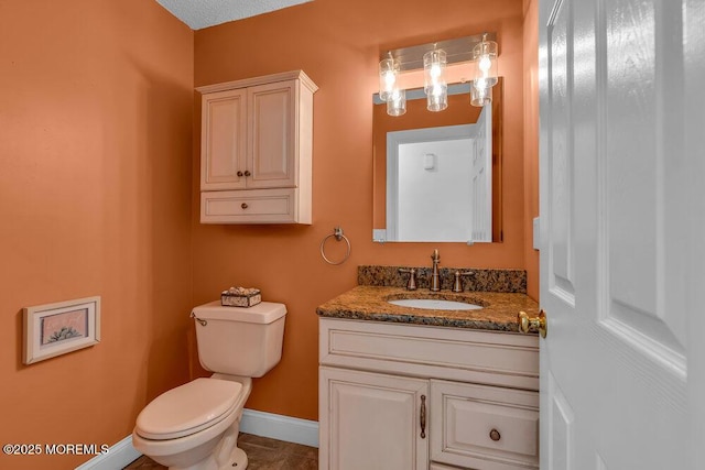 bathroom featuring baseboards, vanity, and toilet