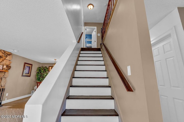 stairway featuring baseboards and a textured ceiling