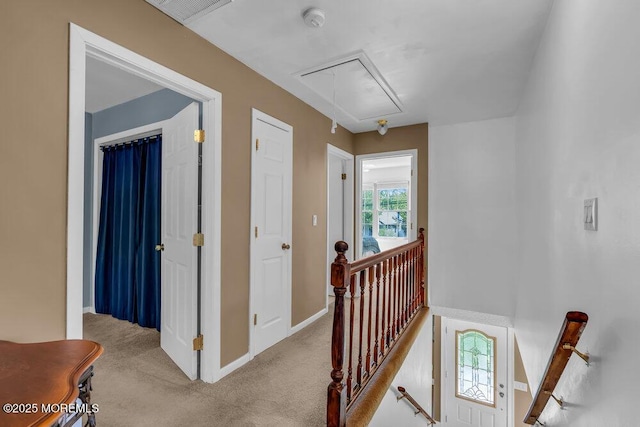 corridor with attic access, visible vents, baseboards, an upstairs landing, and carpet flooring