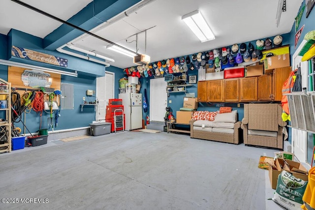 garage with freestanding refrigerator, a garage door opener, and electric panel