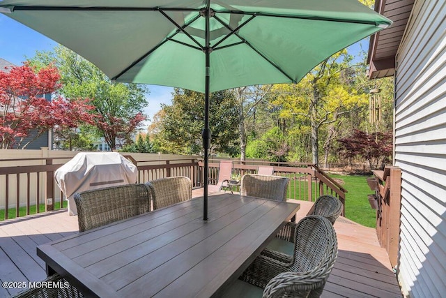deck with a yard, outdoor dining area, a fenced backyard, and a grill
