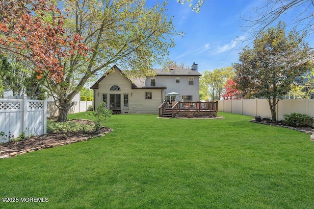 back of house with a chimney, a fenced backyard, a yard, and a deck