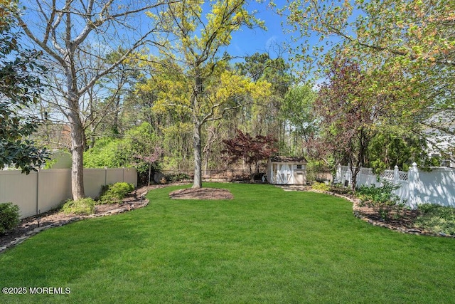 view of yard featuring an outbuilding, a fenced backyard, and a storage unit