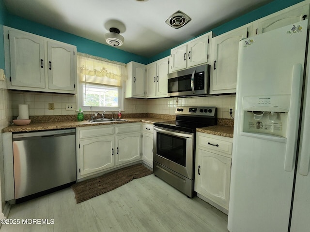 kitchen with a sink, backsplash, stainless steel appliances, and light wood-type flooring