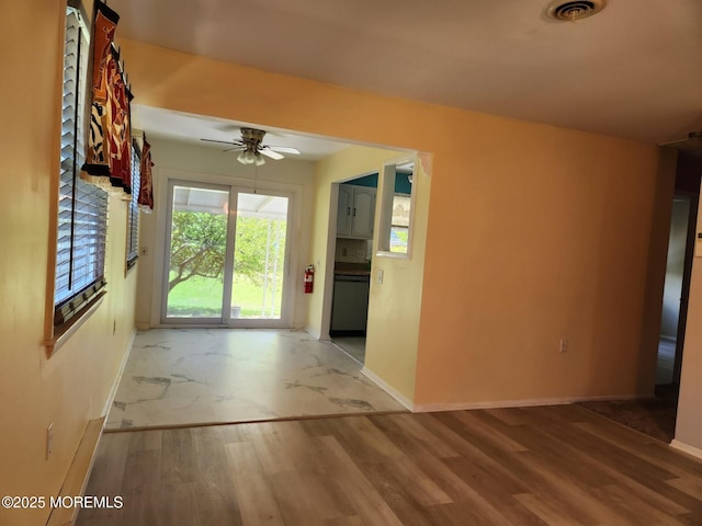 unfurnished living room featuring a ceiling fan, baseboards, visible vents, and wood finished floors