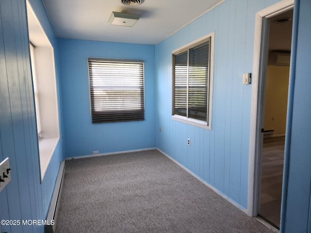 carpeted empty room with an AC wall unit, baseboards, a healthy amount of sunlight, and baseboard heating