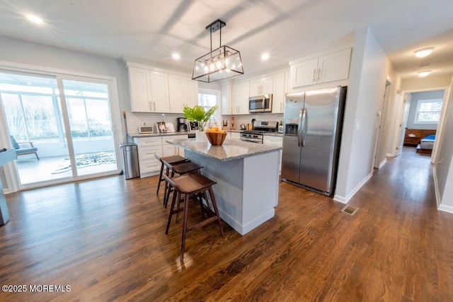 kitchen with stainless steel appliances, a kitchen island, recessed lighting, tasteful backsplash, and white cabinets