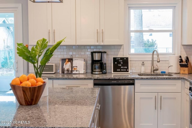 kitchen with dishwasher, a sink, white cabinets, tasteful backsplash, and light stone counters