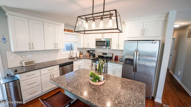 kitchen with appliances with stainless steel finishes, a sink, white cabinets, and dark wood-style floors