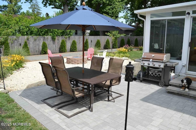 view of patio featuring grilling area, outdoor dining space, fence, and an outdoor fire pit