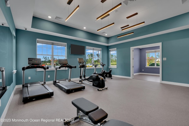 workout area featuring baseboards, recessed lighting, a raised ceiling, and visible vents