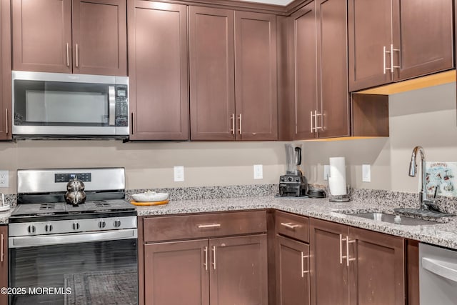 kitchen featuring light stone countertops, appliances with stainless steel finishes, and a sink