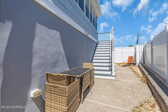 view of patio with fence and stairs