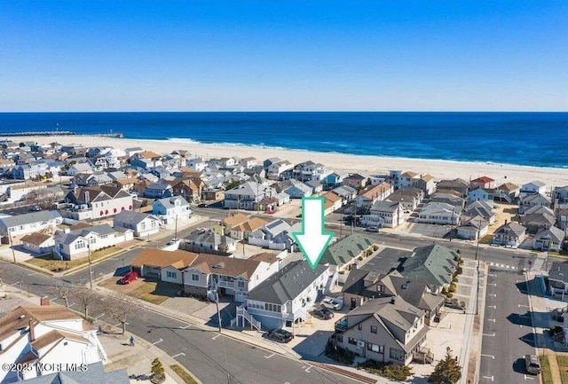 bird's eye view with a water view, a view of the beach, and a residential view