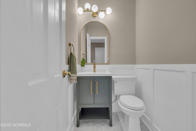 63 Carriage Hill Dr, Colts Neck, NJ 07722 - half bath featuring vanity, a wainscoted wall, toilet, marble finish floor, and a decorative wall