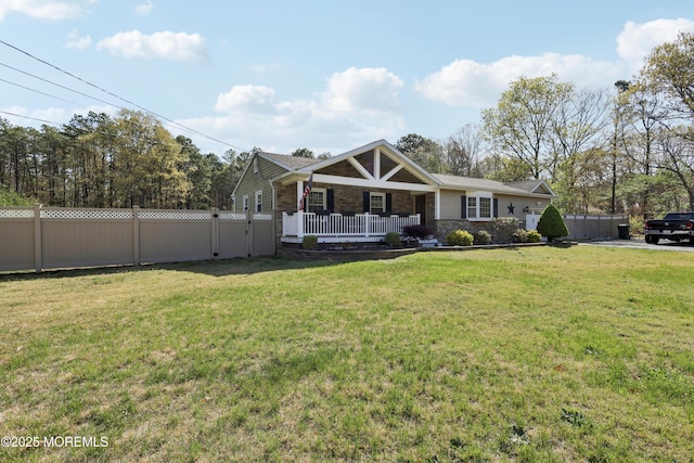view of front of property with fence, covered porch, a front lawn, and stone siding