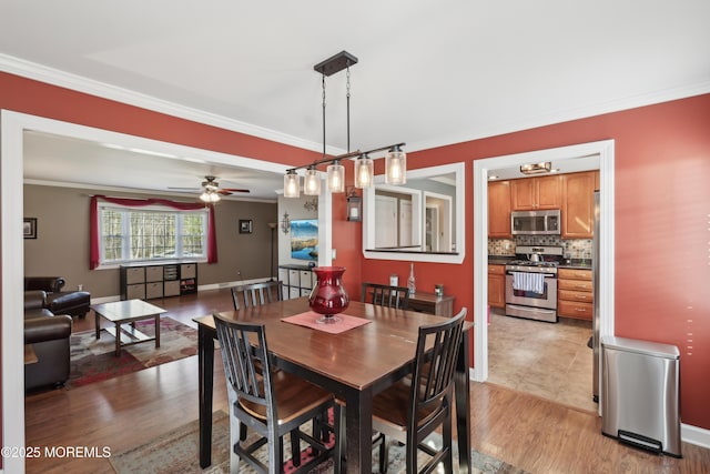 dining area with baseboards, ornamental molding, ceiling fan, and light wood-type flooring