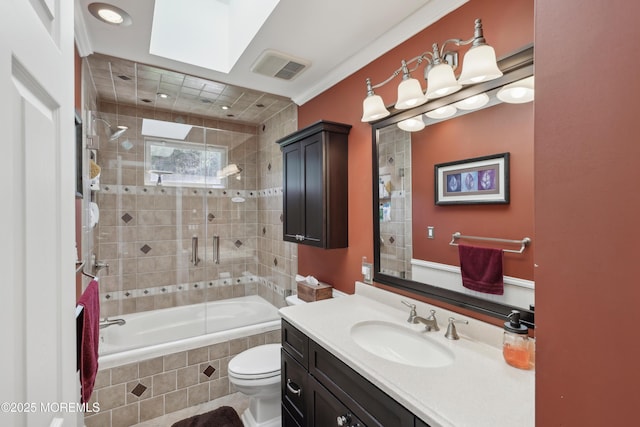 bathroom with vanity, tiled shower / bath, toilet, and visible vents
