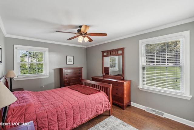 bedroom with baseboards, ornamental molding, wood finished floors, and visible vents