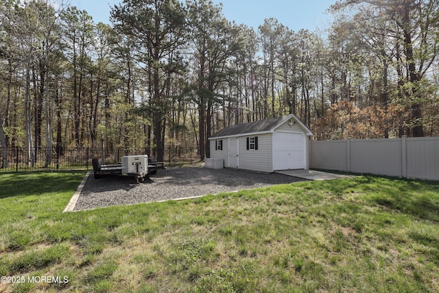 view of yard with a detached garage, fence, and an outbuilding