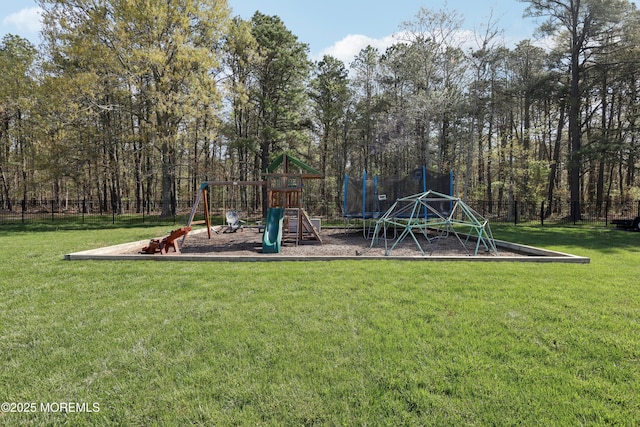 community playground featuring a trampoline, fence, and a yard