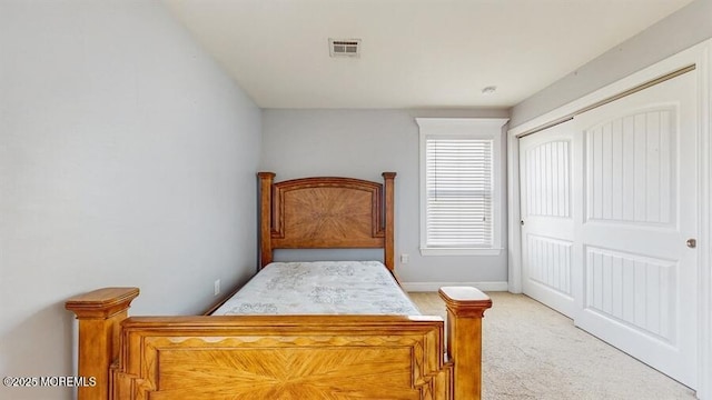 bedroom featuring visible vents, baseboards, a closet, and light colored carpet