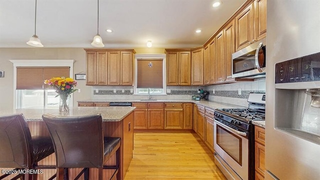 kitchen with ornamental molding, a kitchen bar, a sink, appliances with stainless steel finishes, and backsplash
