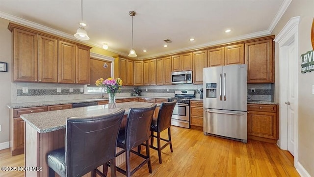 kitchen with brown cabinetry, decorative backsplash, light wood-style floors, and appliances with stainless steel finishes