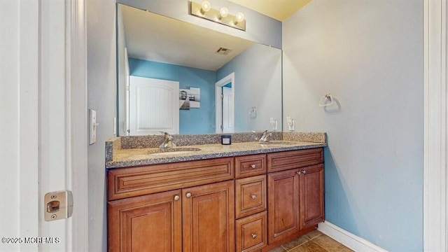 bathroom featuring double vanity, a sink, baseboards, and tile patterned floors