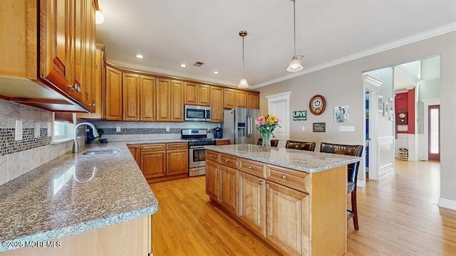 kitchen with a kitchen breakfast bar, appliances with stainless steel finishes, a sink, and light wood-style floors