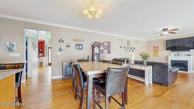 dining area with crown molding, light wood-style floors, and visible vents