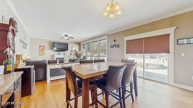 dining room featuring crown molding, light wood finished floors, and ceiling fan with notable chandelier