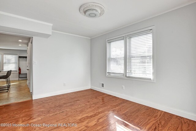 unfurnished room featuring crown molding, baseboards, visible vents, and light wood-type flooring