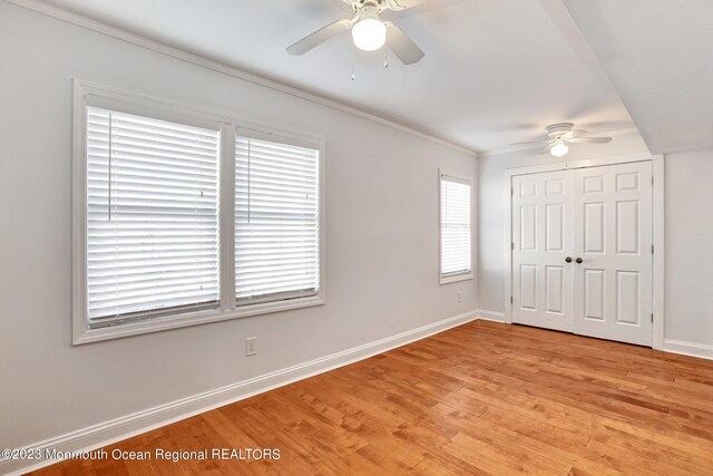 unfurnished bedroom featuring light wood-type flooring, a ceiling fan, baseboards, and a closet