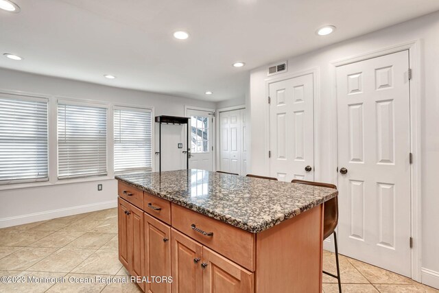 kitchen featuring light tile patterned flooring, baseboards, recessed lighting, and a center island