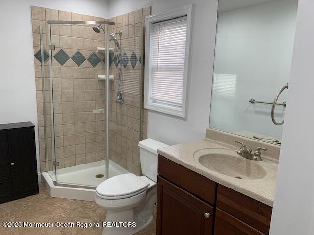 bathroom featuring vanity, toilet, tile patterned floors, and a stall shower