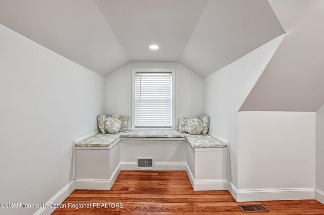 additional living space with baseboards, visible vents, light wood-style flooring, and vaulted ceiling