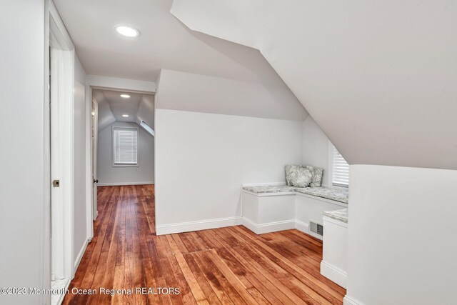 bonus room with visible vents, plenty of natural light, lofted ceiling, and light wood-style floors