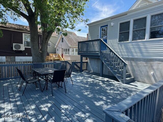 wooden terrace featuring outdoor dining space, ac unit, and stairs