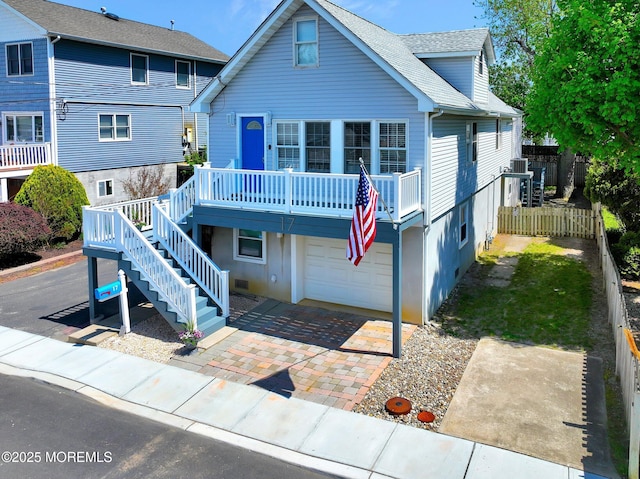 view of front facade featuring stairway, fence, a shingled roof, and a garage