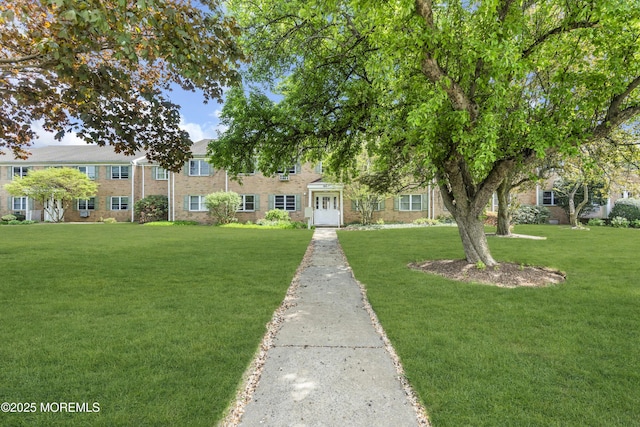 multi unit property with brick siding and a front yard