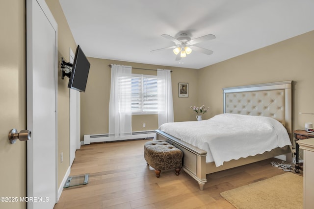 bedroom with a ceiling fan, light wood finished floors, and baseboard heating