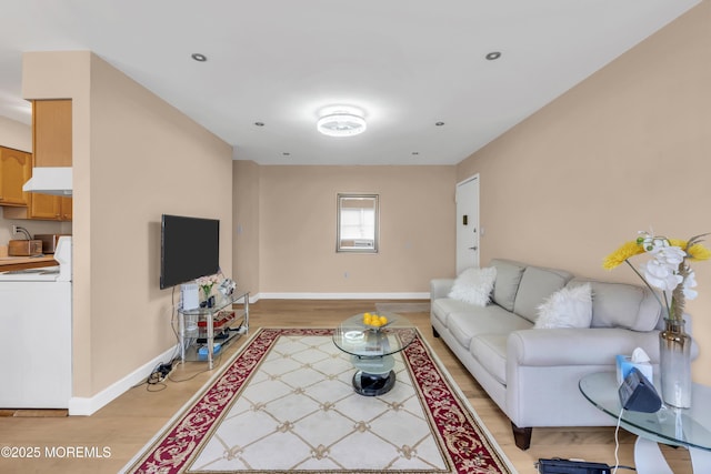 living room featuring washer / dryer, baseboards, recessed lighting, and light wood finished floors