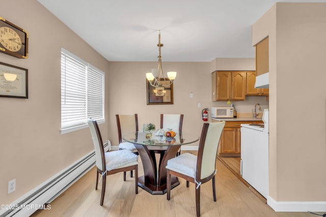 dining space with an inviting chandelier, baseboards, baseboard heating, and light wood-style flooring